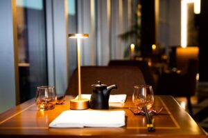 A rechargeable table lamp lit on a restaurant table laid for dinner