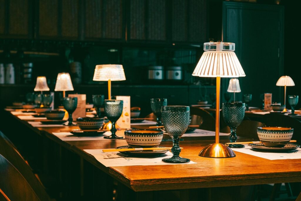 Cordless table lamps spaced along a long banquet table in a dark dining room