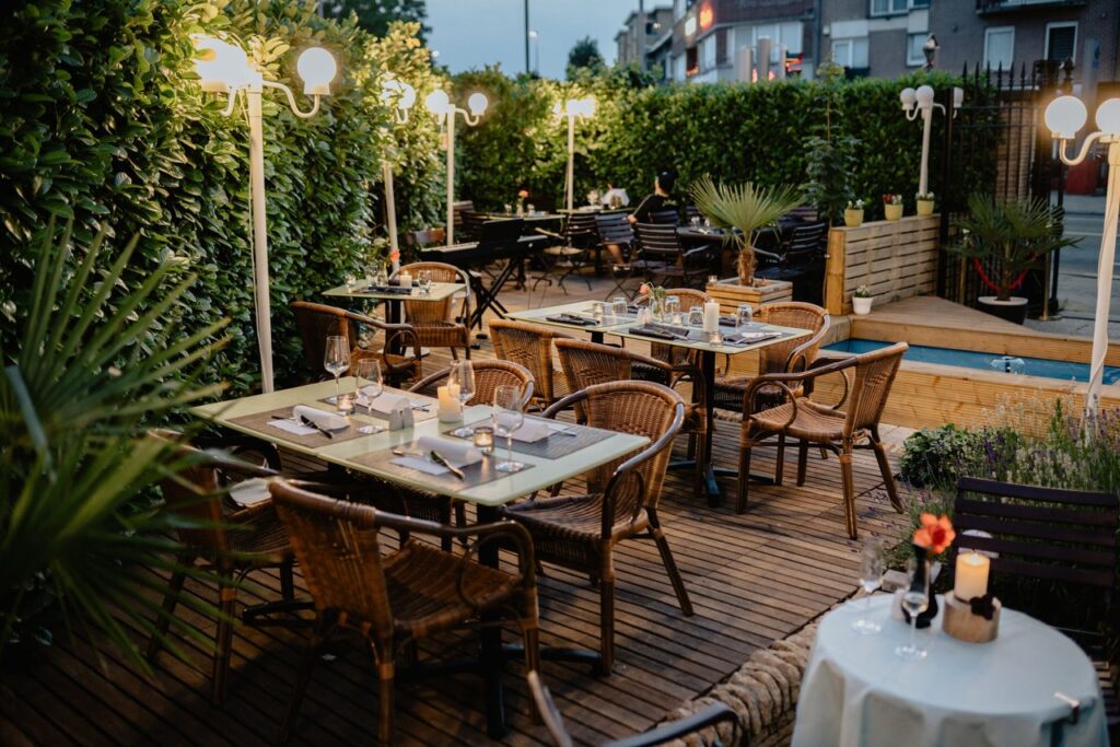 Outdoor dining tables each lit by a cordless lamp on a terrace at dusk
