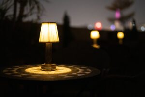 A portable lamp lit on an outdoor balcony table at dusk