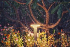 A solar garden lamp glowing among planting at dusk