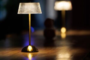 A cordless table lamp with a faceted shade glowing against bokeh lights